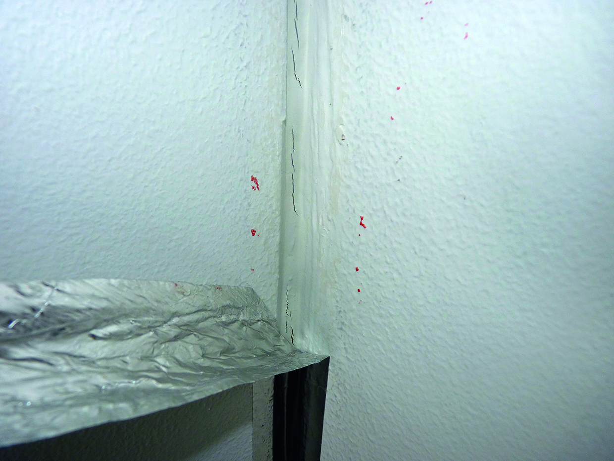 An interior light grey and cracked wall joint in a classroom.